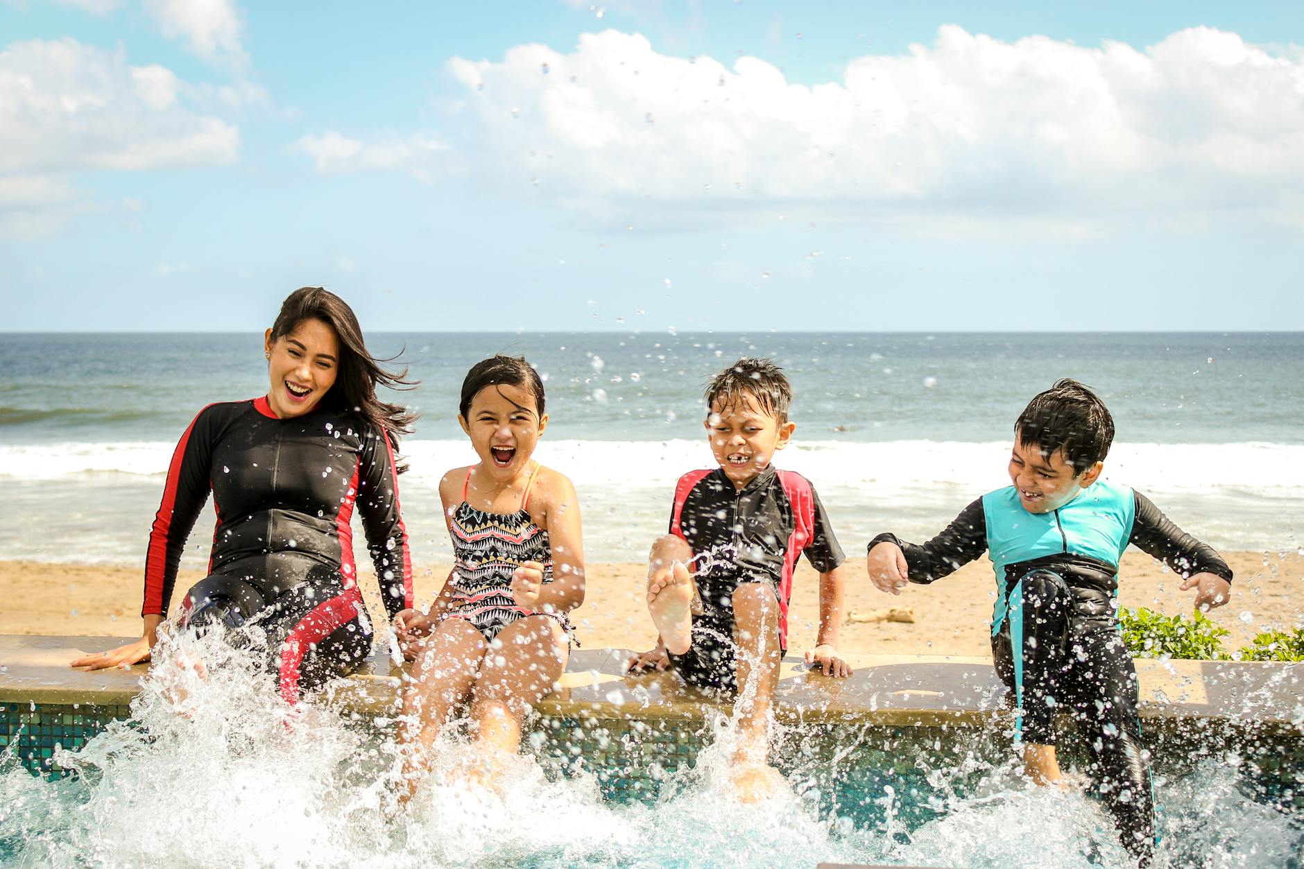 woman and three children playing water